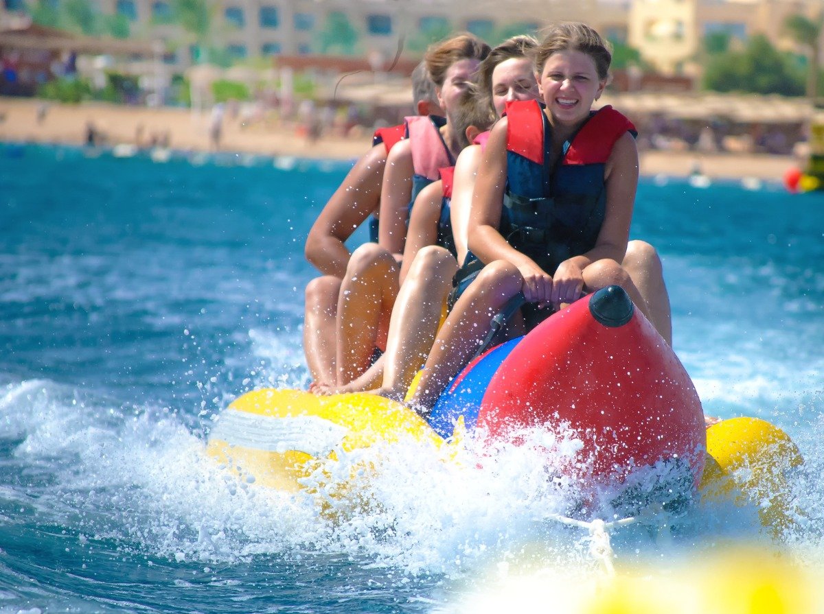 Personas disfrutando un paseo en banana boat remolcado por lancha